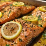 Flavor-packed baked salmon resting on a plate, surrounded by lemon slices and fresh herbs.
