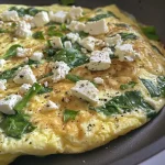 Close-up of a juicy spinach and feta omelet showing the filling and golden-brown edges.