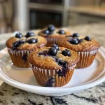 Deliciously baked blueberry protein muffin with a soft texture and blueberries peeking through.