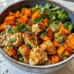 Delicious chicken and sweet potato dish garnished with fresh herbs on a wooden table.