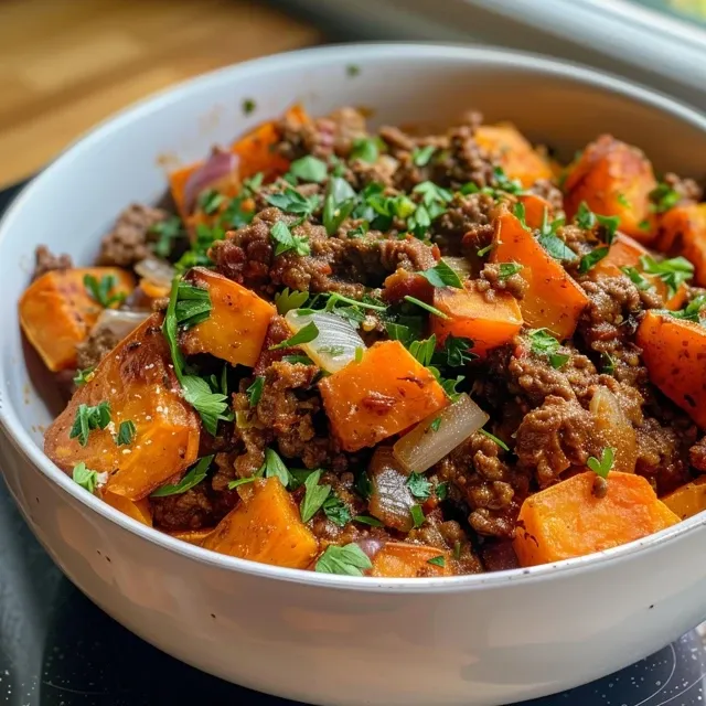 Side angle of a delicious beef bowl showcasing diced sweet potatoes and parsley.