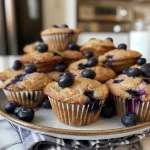 Juicy blueberry muffins on a white plate, showcasing a soft and fluffy interior.