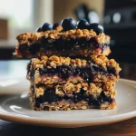 Delicious-looking blueberry oat bars cut into squares, featuring glistening blueberries.