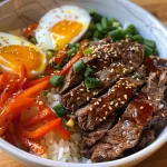 A delicious bowl of Korean beef and rice, showcasing sliced bell peppers, carrots, and green onions.
