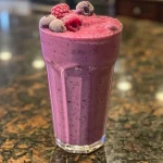 Side view of a creamy triple berry smoothie with visible fruit textures.