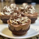 Close-up side view of chocolate cheesecake dessert cups with whipped topping and chocolate shavings.
