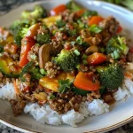 A close-up view of a spicy ground beef stir-fry bowl with vibrant garlic veggies.