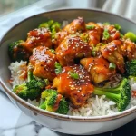 Juicy sticky chicken served over rice with broccoli in a rustic bowl.