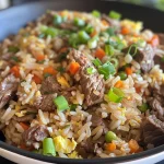 Side view of a bowl featuring beef fried rice with a sprinkle of green onions on top.
