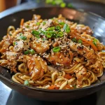 Close-up of juicy Chicken Teriyaki Noodles with sliced chicken and colorful garnishes.