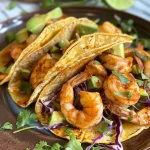 Close-up of juicy shrimp tacos with vibrant toppings.