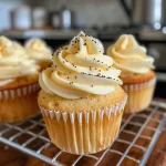 Side view of a fluffy vanilla cupcake topped with white frosting and colorful sprinkles.