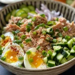 Close-up of a Tuna & Egg Protein Bowl featuring tuna, soft-boiled eggs, and fresh vegetables.