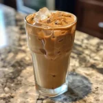 Close-up of a creamy coconut milk iced coffee in a glass with ice cubes.