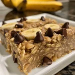 Close-up of golden-brown banana oatmeal bars with chocolate chips and walnuts.