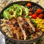 Close-up view of a colorful chicken quinoa bowl with sliced grilled chicken, black beans, corn, and avocado.