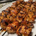 Close-up view of juicy BBQ chicken skewers on a wooden platter.