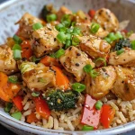 A close-up view of a colorful chicken veggie rice bowl topped with green onions.