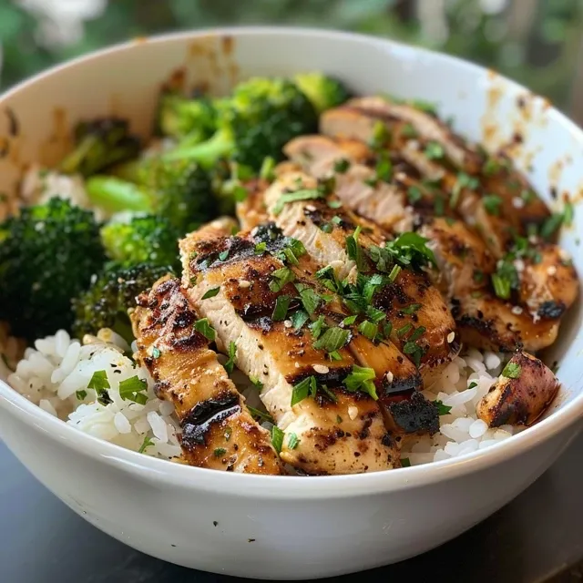 Colorful grilled chicken and broccoli rice bowl with fresh parsley on top.