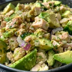 A close-up view of a vibrant avocado tuna salad with fresh ingredients.