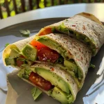A side view of a fresh avocado wrap filled with vibrant ingredients.