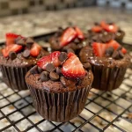 A close-up side view of moist strawberry chocolate muffins topped with a sprinkle of sugar.