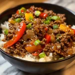 A close-up view of a juicy Beef and Pepper Rice Bowl, highlighting vibrant bell peppers and ground beef over rice.