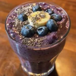 Close-up view of a creamy Blueberry Banana Oat Smoothie in a clear glass.
