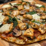A close-up side view of Chicken Rice Cake Pizza topped with diced chicken, vegetables, and melted cheese.