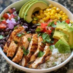 Close-up of a colorful Chili Lime Chicken Burrito Bowl featuring chicken, rice, beans, and avocado.