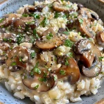 A close-up view of a creamy butter garlic mushroom rice bowl garnished with herbs.