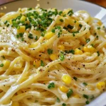 Creamy corn pasta dish with vibrant green onions and sweet corn kernels.