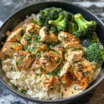 A close-up side view of creamy garlic chicken rice bowls topped with parsley.