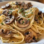A close-up view of creamy miso mushroom pasta garnished with fresh thyme.