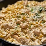 A close-up view of creamy Dairy Free Chicken Alfredo with gluten-free farfalle pasta and diced chicken.