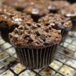 A side view of juicy double chocolate muffins with a glossy chocolate topping.