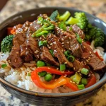 A close-up view of a juicy teriyaki beef bowl garnished with fresh vegetables.