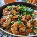 A close-up side view of a Garlic Soy Shrimp Rice Bowl topped with green onions and sesame seeds.
