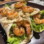 Close-up view of zesty grilled shrimp Caesar wraps filled with shrimp, lettuce, and dressing.