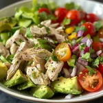 Close-up view of a colorful avocado chicken salad in a bowl, showcasing fresh ingredients.