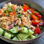 A close-up side view of a colorful high-protein chicken salad in a bowl, showcasing fresh ingredients.