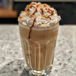 Close-up of a glass filled with iced caramel latte, showcasing layers of milk, espresso, and caramel syrup.