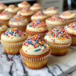 Close-up view of a colorful mini cupcake topped with creamy frosting.
