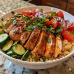 Close-up view of a Moroccan Chicken Couscous Bowl featuring diced chicken, colorful vegetables, and creamy yogurt on top.