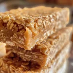 Close-up image of stacked no-bake oat bars with a smooth peanut butter layer.