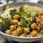 A close-up side view of a bowl filled with roasted broccoli and chickpeas.