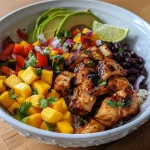 Close-up view of a colorful Spicy Mango Chicken Rice Bowl with diced chicken, mango, and avocado.