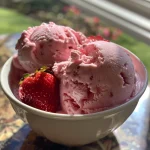 Close-up view of creamy strawberry frozen yogurt in a cup, garnished with fresh strawberry slices.