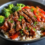 A close-up side view of a bowl filled with teriyaki beef, broccoli, and rice.