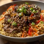 Close-up side view of Teriyaki Beef Noodles with colorful vegetables and glossy sauce.